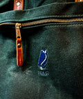 Close-up of a green bag with a zipper and a logo on a dark background