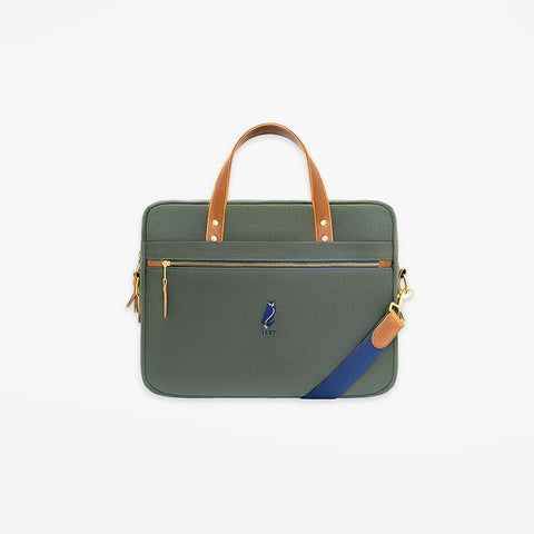 Green handbag with brown handle and blue strap on a white background